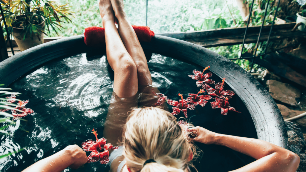 Mulher  relaxando em banho de flores em banheira. 