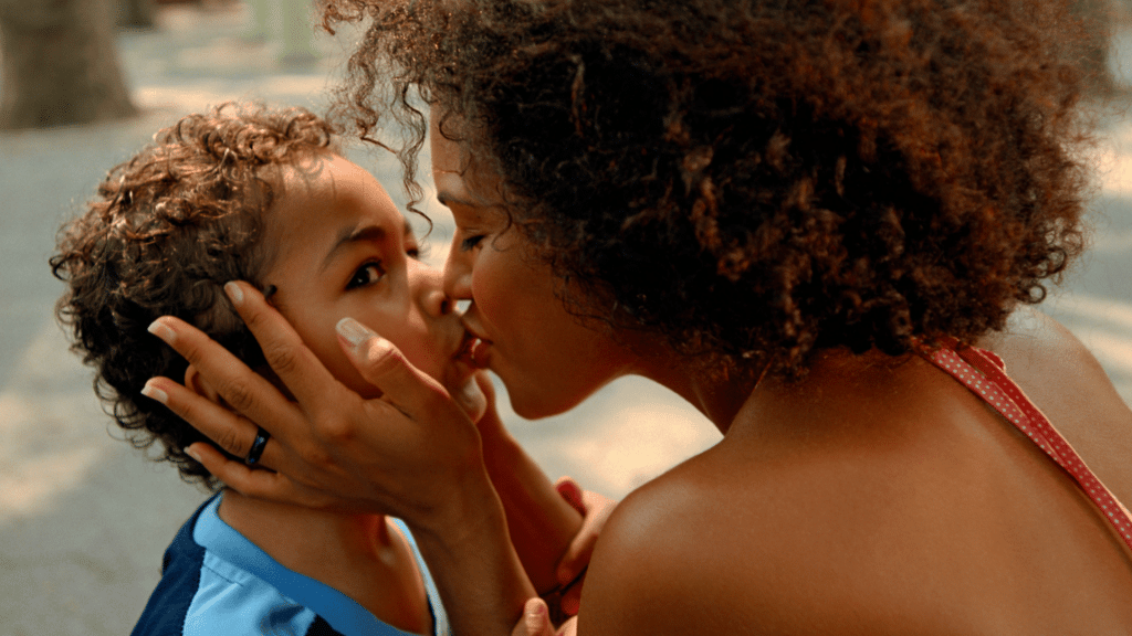 Mãe beijando seu filho na boca no parque. 