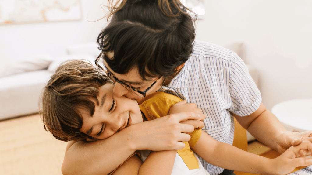 Mãe beijando seu filho na bochecha enquanto o abraça. 