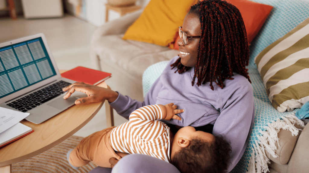 Mãe na frente de um laptop segurando seu bebê no colo