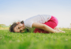 Criança de joelhos e com a cabeça deitada na grama