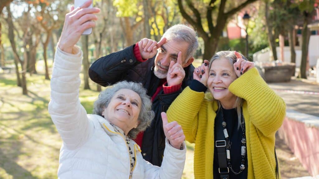 Três idosos tirando foto em uma praça