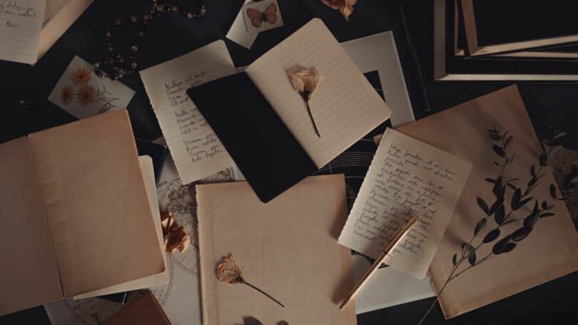 Vários livros de poesia abertos, em cima da mesa, rosas secas sobre alguns