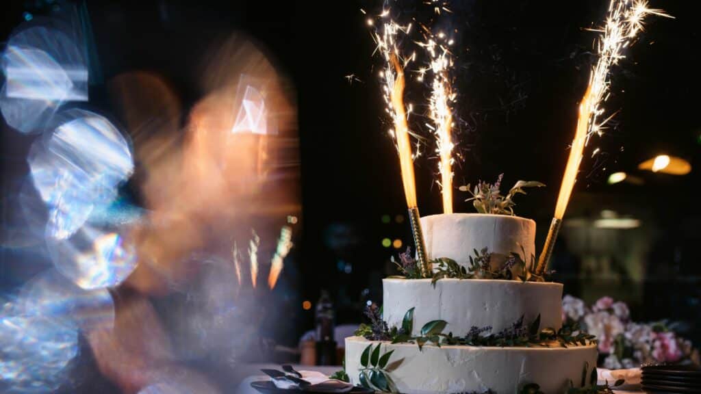 Bolo de casamento em cima de uma mesa com fogos de artifício em volta dele