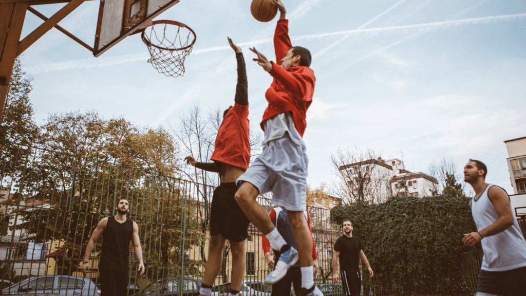 Homens jogando basquete em quadra aberrta. Representação de atividade de lazer. 