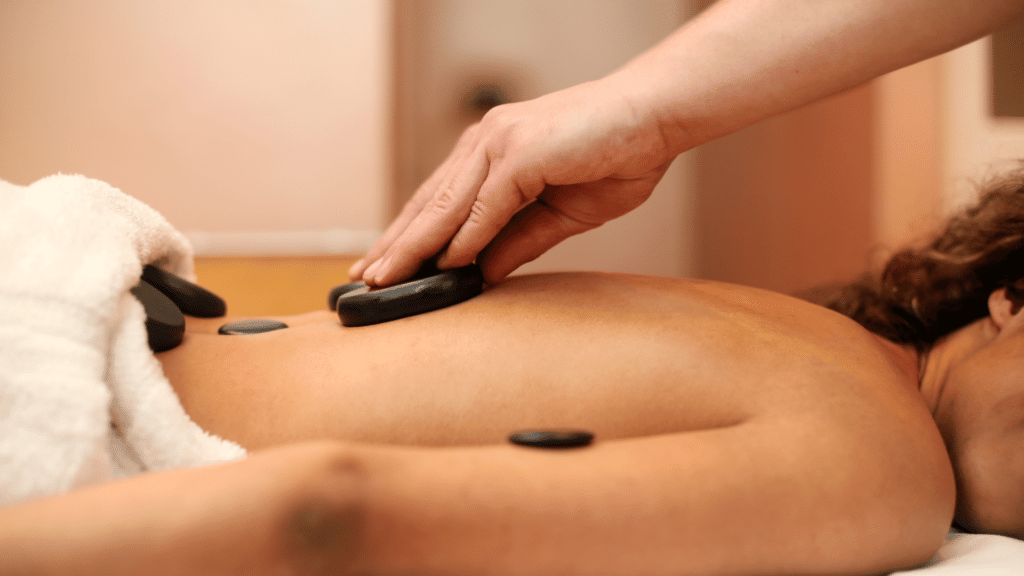 Pessoa recebendo massagem com pedras vulcânicas.