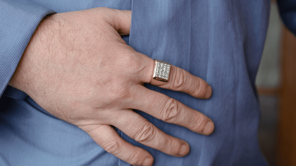 Homem usando anel de ouro com brilhante em dedo indicador. 