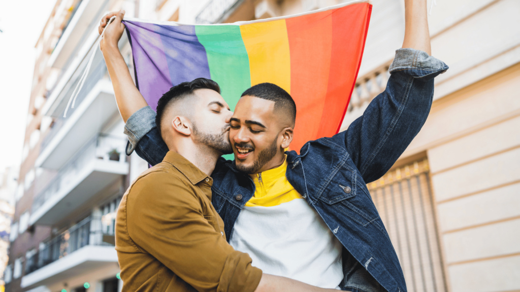 Casal gay se abraçando enquanto segura bandeira LGBTQIA+