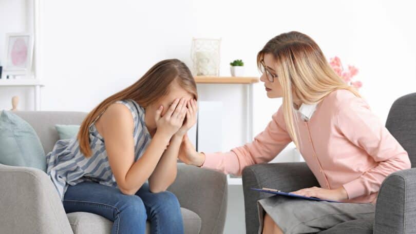 Psicanalista consolando uma paciente em seu consultório