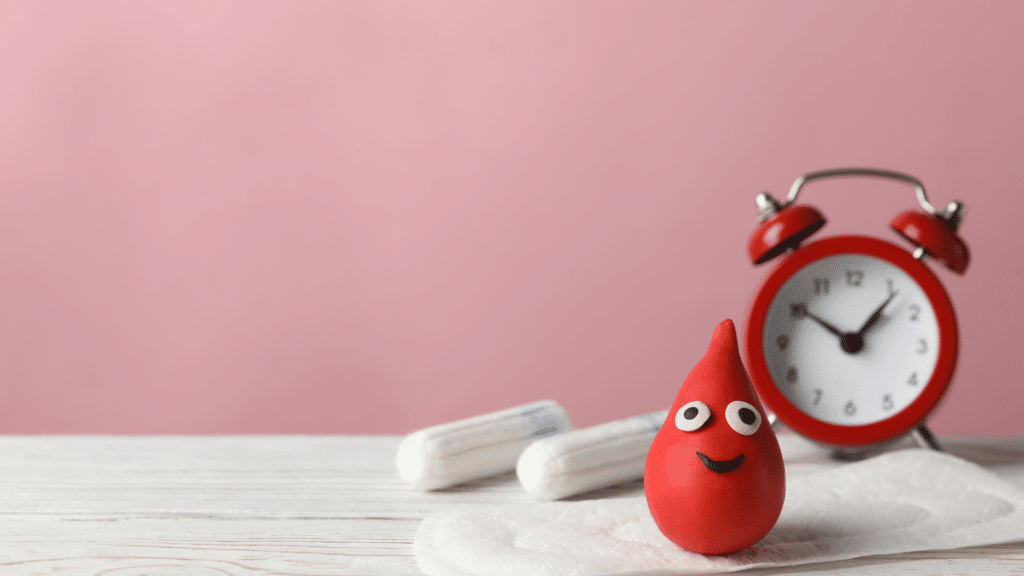 Representação 3D de uma gota de sangue, um relógio e absorventes