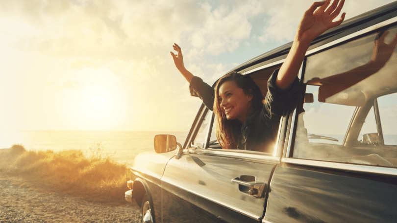 Mulher com braços levantados na janela de um carro