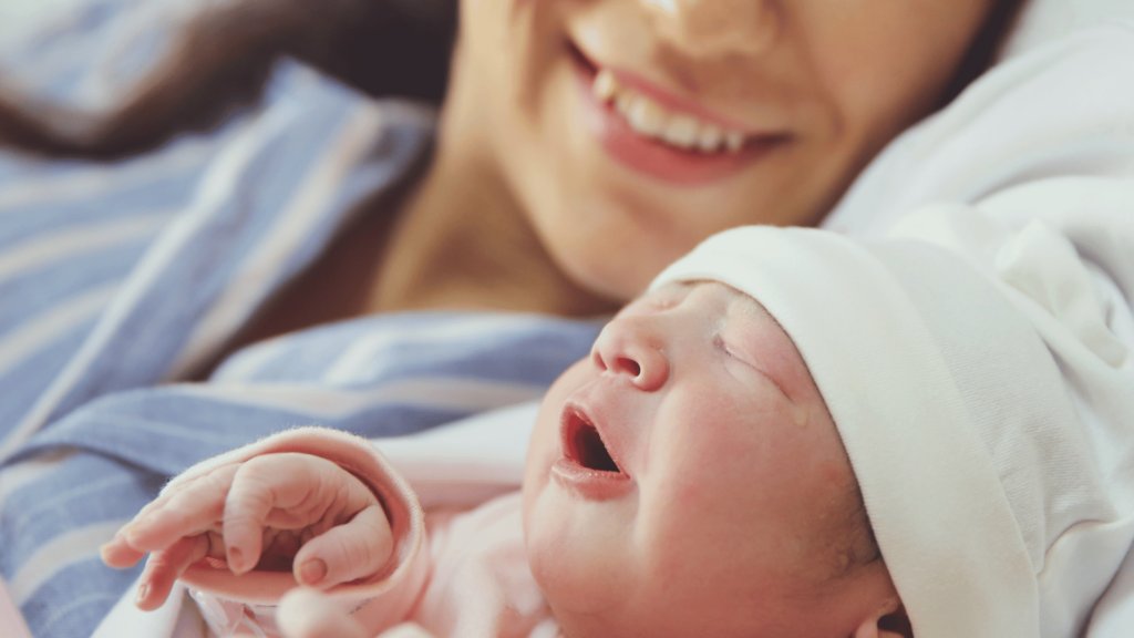 Bebê recém-nascido com sua mãe. Ela sorri enquanto olha para o seu filho. 