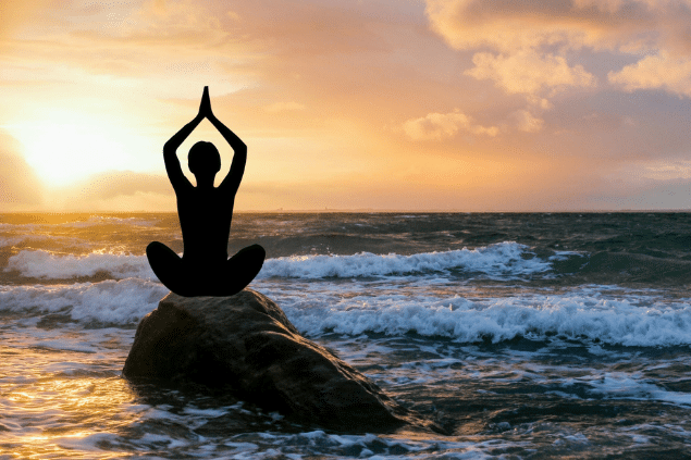 Mulher meditando no meio do oceano em cima de uma pedra