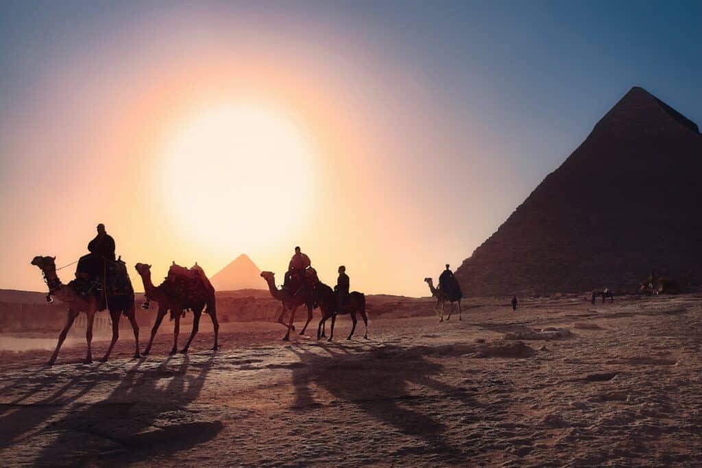 Pessoas montadas em camelos perto das pirâmides do Egito