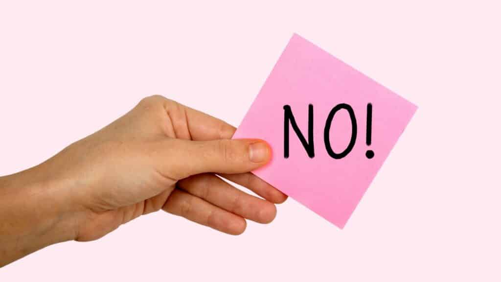 Mão segurando papel rosa, sinalizando um "Não".  