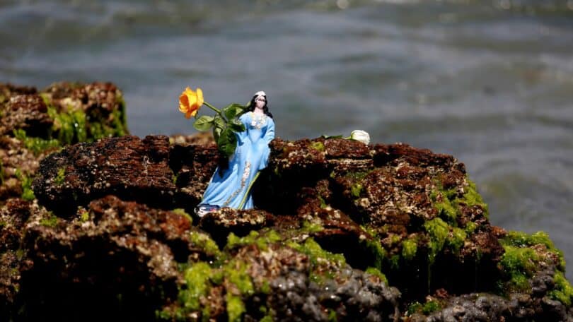 Estátua de Iemanjá em cima de uma rocha a beira mar