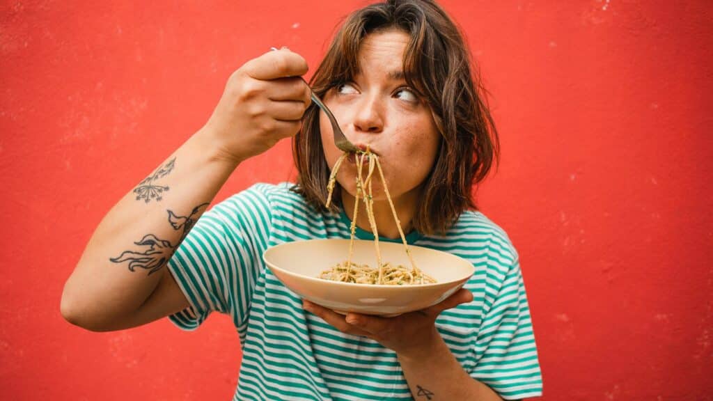 Mulher comendo macarrão em um fundo vermelho