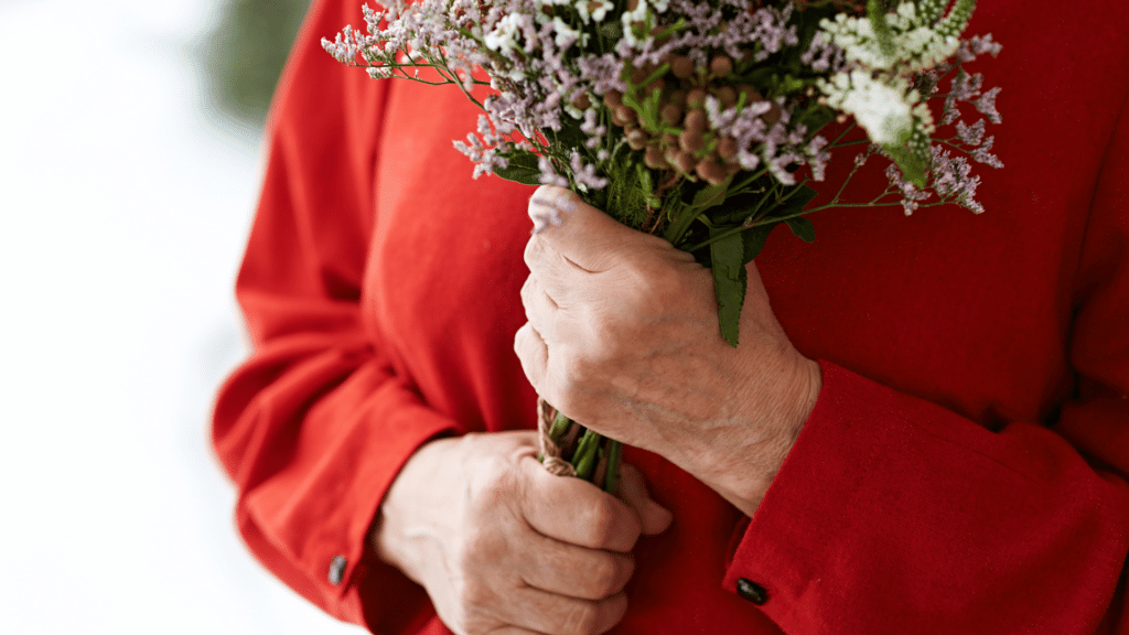 Mãos de uma mulher segurando um buquê de flores. 