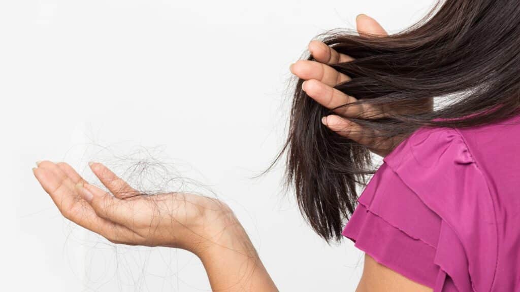 Mulher com fios de cabelo na mão. Conceito de queda de cabelo.