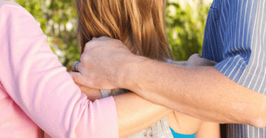 Pais conversando com sua filha, com as mãos sobre suas costas. Conceito de dependência emocional parental.