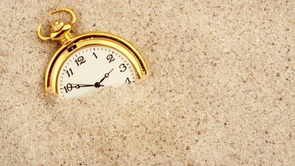 Relógio dourado enterrado na areia