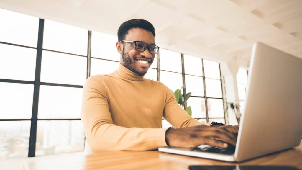 Homem fazendo pesquisas em seu notebook e sorrindo.