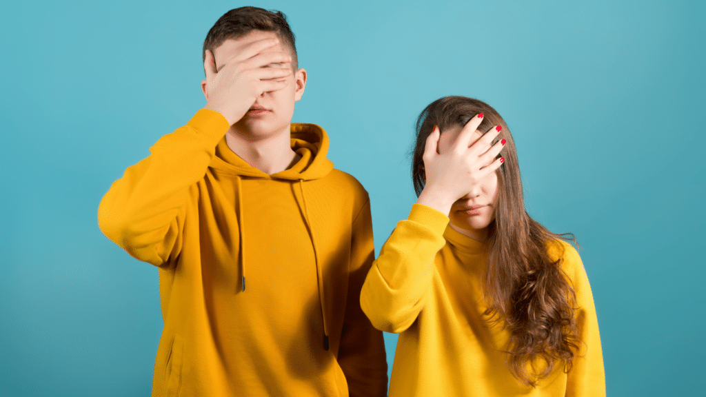 Dois adolescentes com as mãos no rosto, em sinal de frustação. 