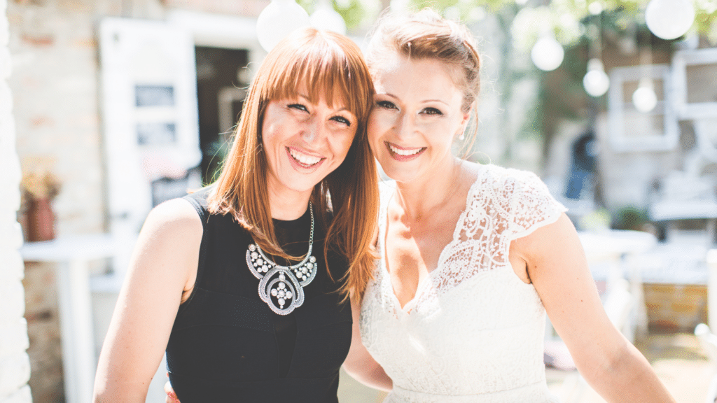 Duas mulheres sorrindo enquanto uma está vestida de noiva
