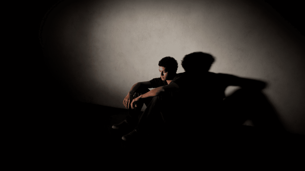 Homem sentado no chão de uma sala totalmente escura
