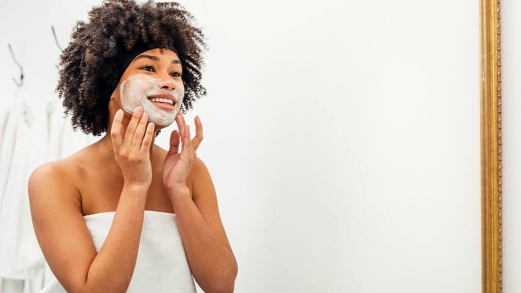 Mulher negra cuidando da pele com máscara facial.