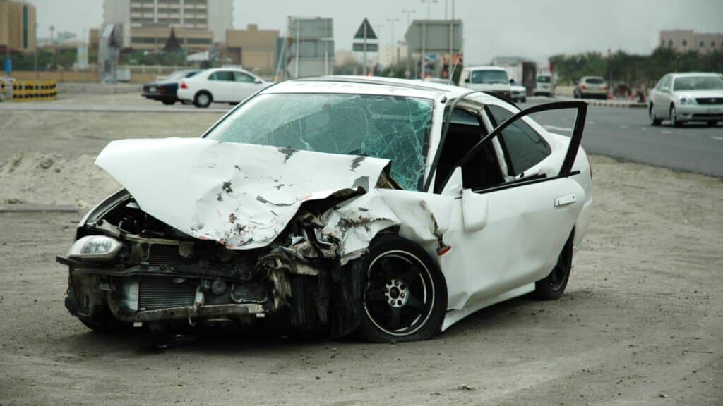 Imagem de um carro branco com a frente batida.