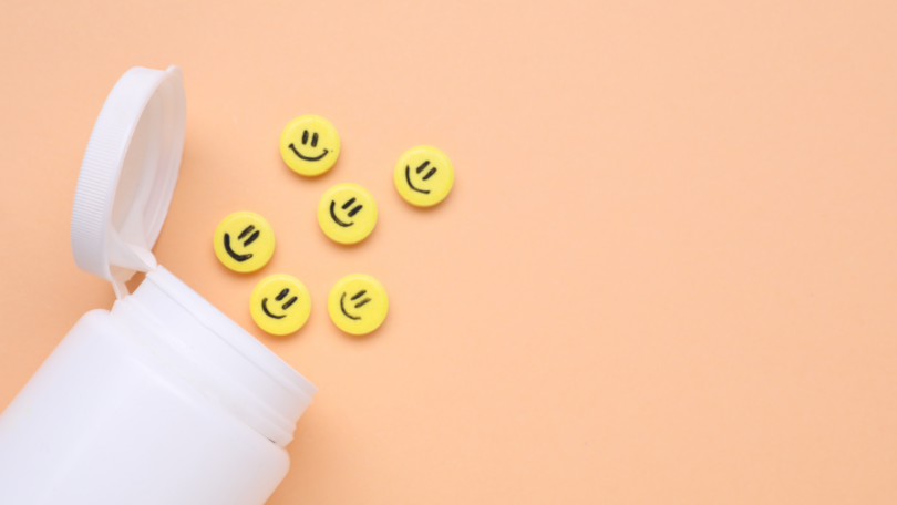 Garrafa e pílulas antidepressivas amarelas com rostos felizes em fundo laranja pálido.