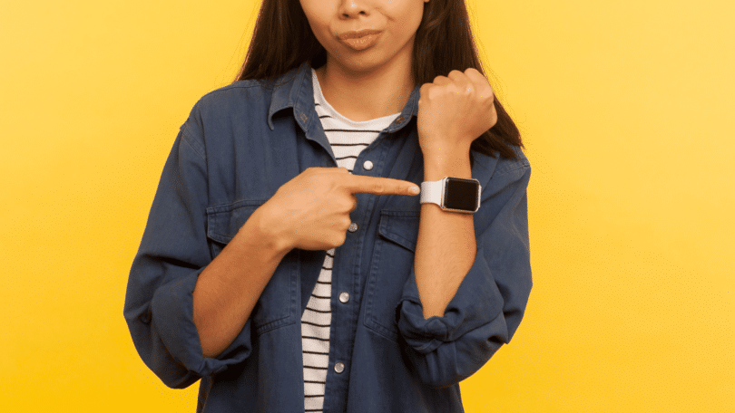Mulher apontando para relógio de pulso, estilo Smartwatch, em seu braço.