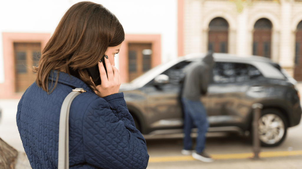 Mulher ligando para pedir ajuda, enquanto vê uma tentativa de roubo de carro.