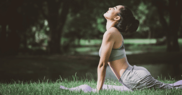 Mulher asiática fazendo posição de yoga no jardim. Ela está se alongando.