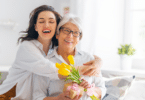 Filha abraçando a mãe enquanto segura uma flor