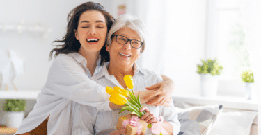 Filha abraçando a mãe enquanto segura uma flor