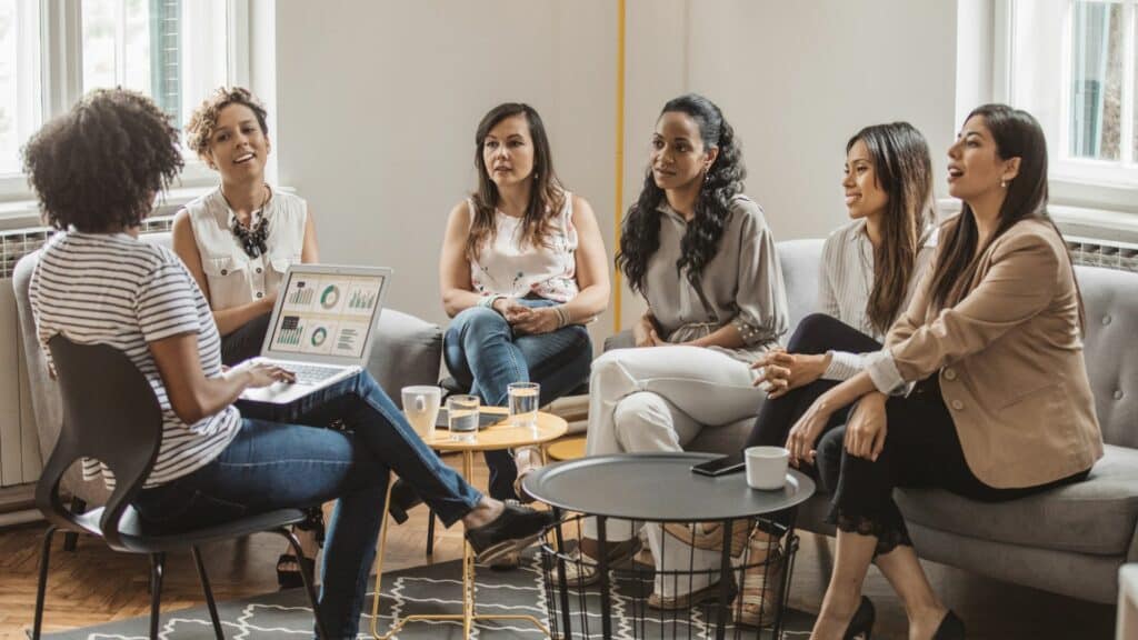 Imagem de várias mulheres reunidos em um espaço de coworking participando de uma reunião de negócios