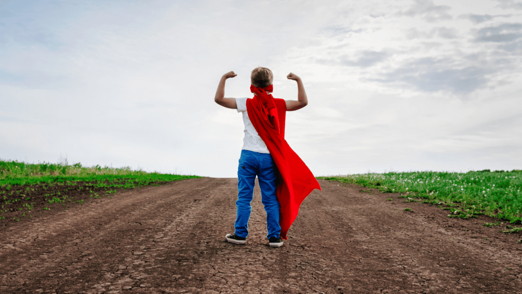 Menininho usando capa de super herói. Conceito de resiliência. 