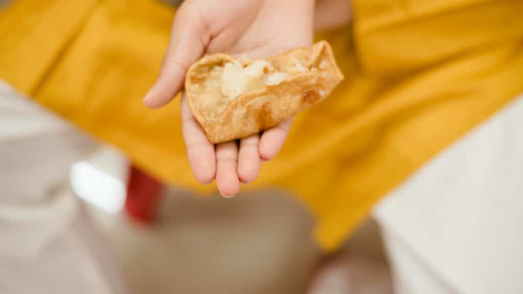 Imagem de uma mão feminina segurando o lanche tradicional Durga Puja