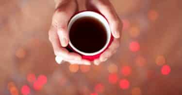 Imagem de uma mão feminina segurando uma xícara de café, representando conceito de como ser uma pessoa melhor.