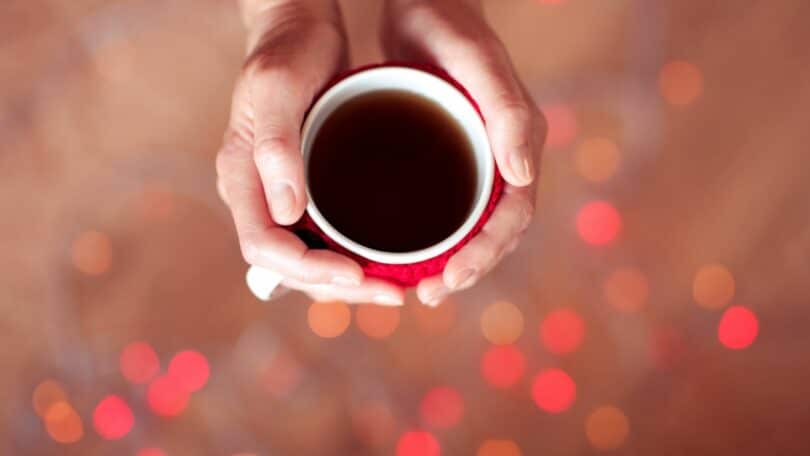 Imagem de uma mão feminina segurando uma xícara de café, representando conceito de como ser uma pessoa melhor.