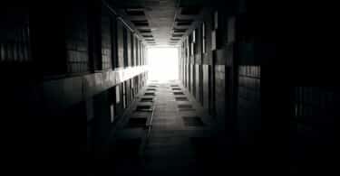 Imagem de um corredor escuro e no fim dele uma porta com uma luz ao fundo.