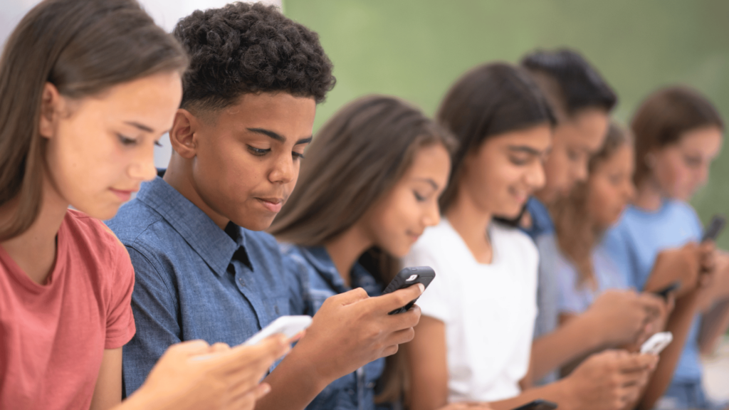 Fila de adolescentes segurando celulares. 