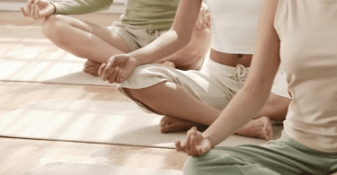 Mulheres sentadas em fileira, fazendo Yoga.
