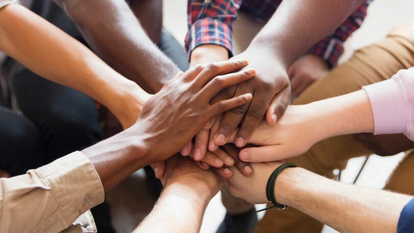 Pessoas dando as mãos em terapia de grupo.