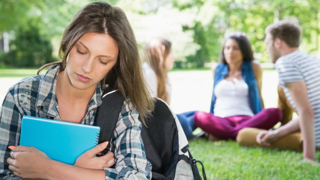Menina sentindo-se excluída de um grupo de amigos da escola. 