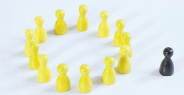 Bonequinhos amarelos e um preto. Conceito de sentir-se excluído.