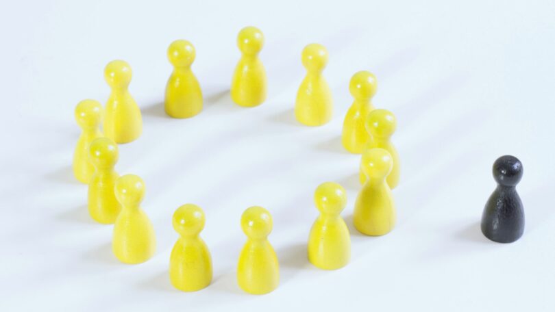Bonequinhos amarelos e um preto. Conceito de sentir-se excluído.