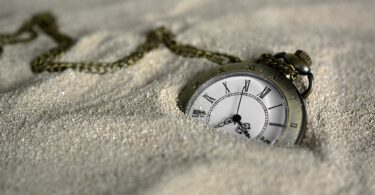 Imagem de um antigo relógio de bolso colocando sobre a areia
